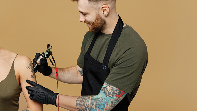 Tatuador haciendo un tatuaje en el brazo